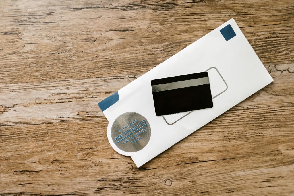 A blank credit card with a pre-approved envelope on a wooden table, showcasing financial opportunities.